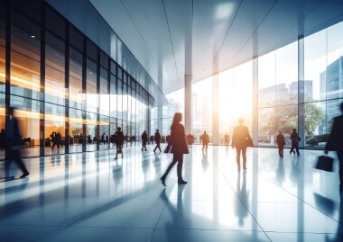 A modern building lobby with people walking towards the light.