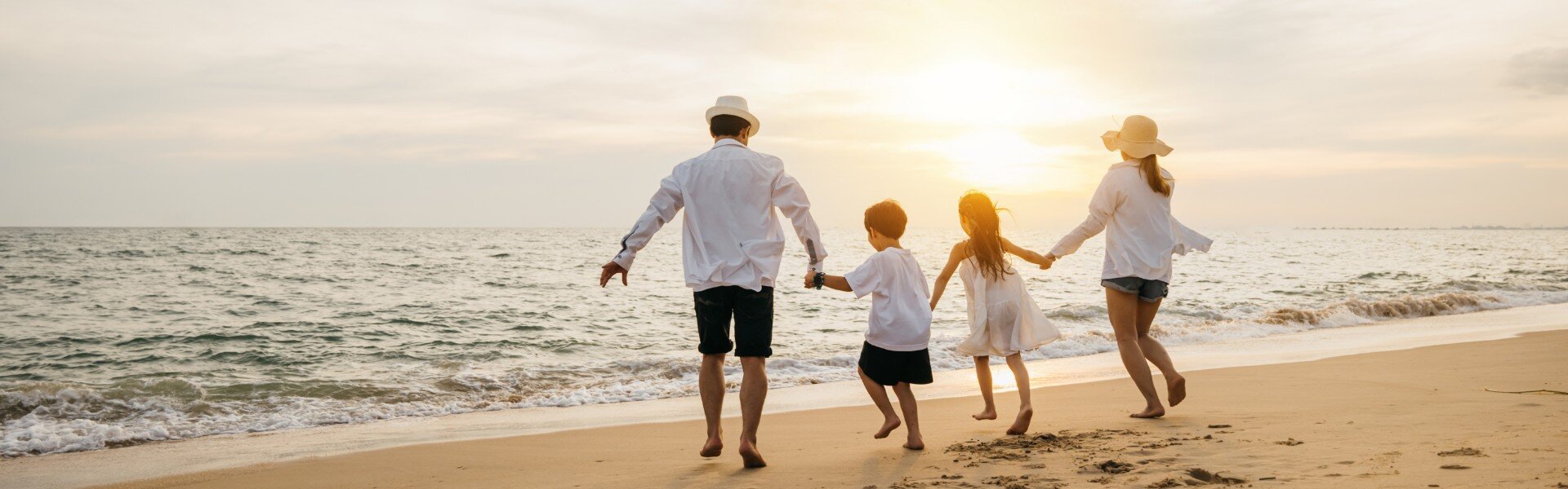 Family walking hand-in-hand on a sandy shoreline